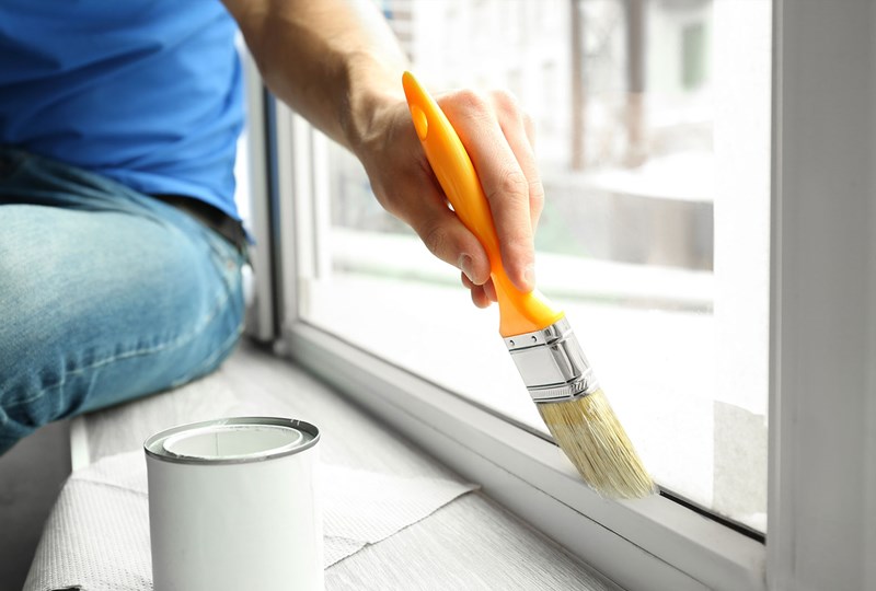 Person painting interior of home window