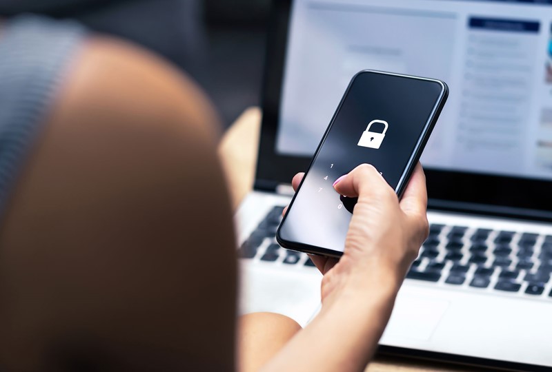 Woman working on a laptop and cell phone simultaneously